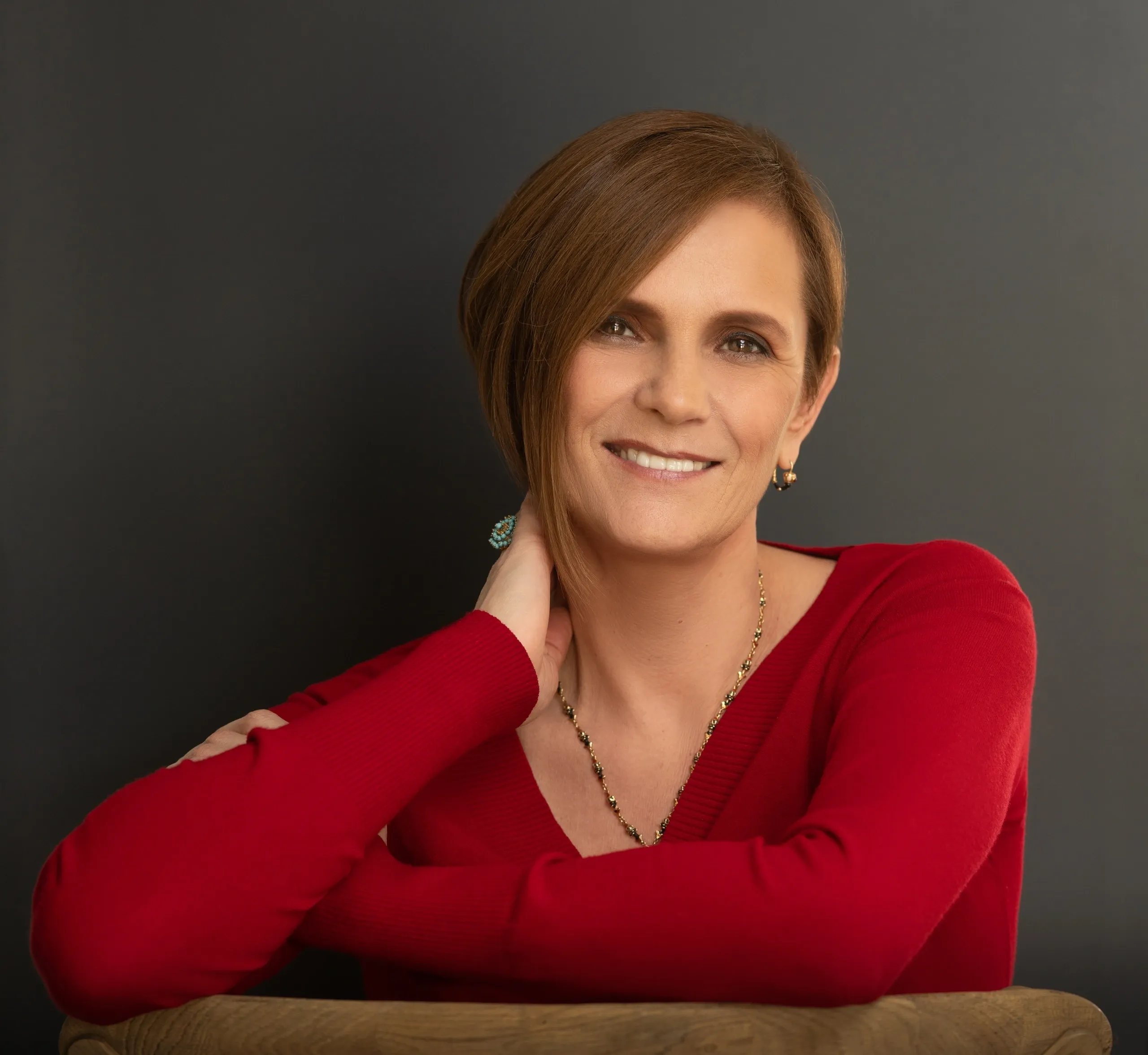 Smiling woman in red sweater against gray