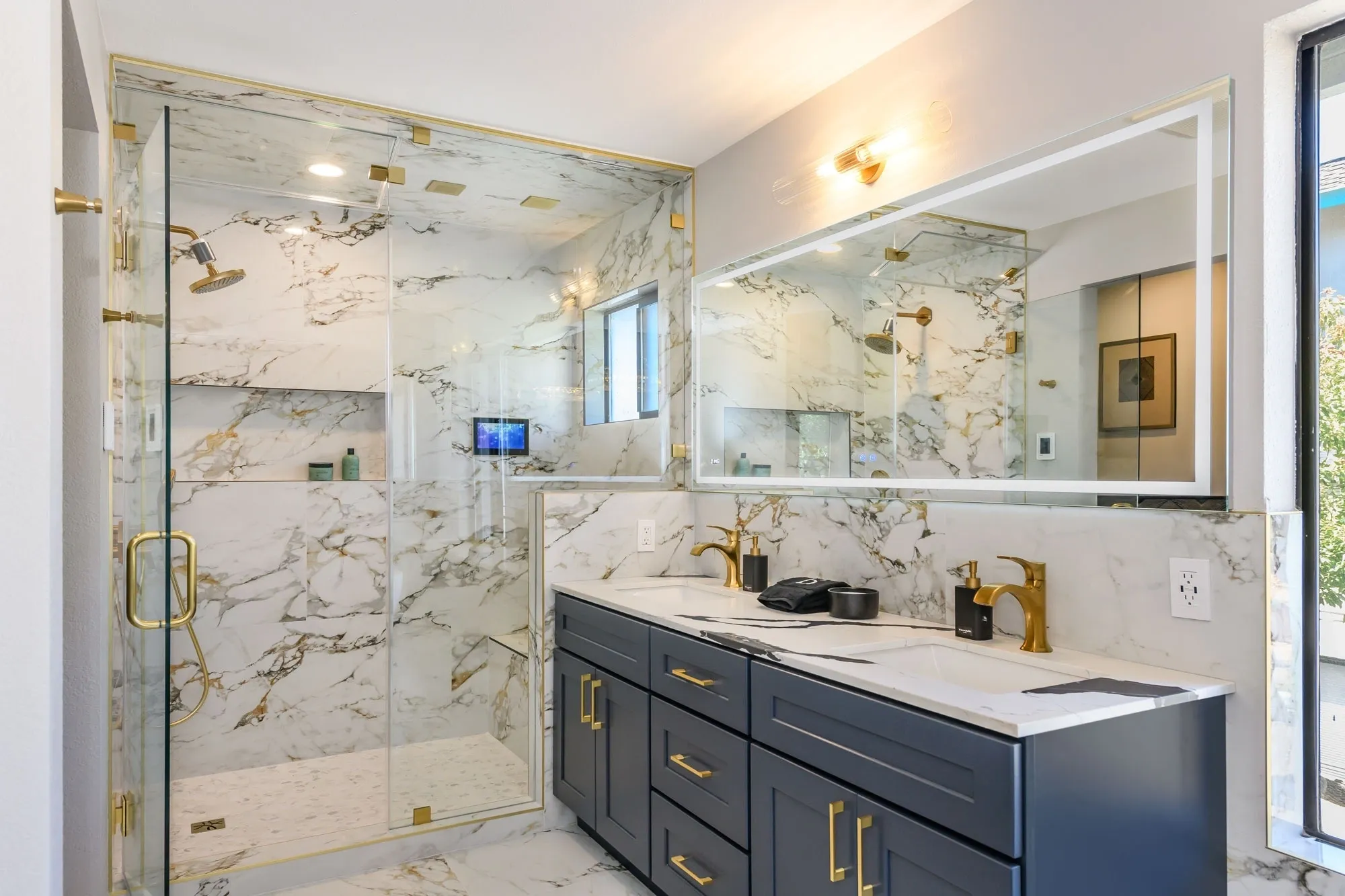 Marble bathroom with navy vanity and gold fixtures