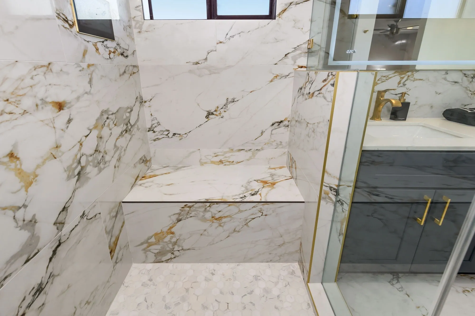 Marble shower with glass door and bench