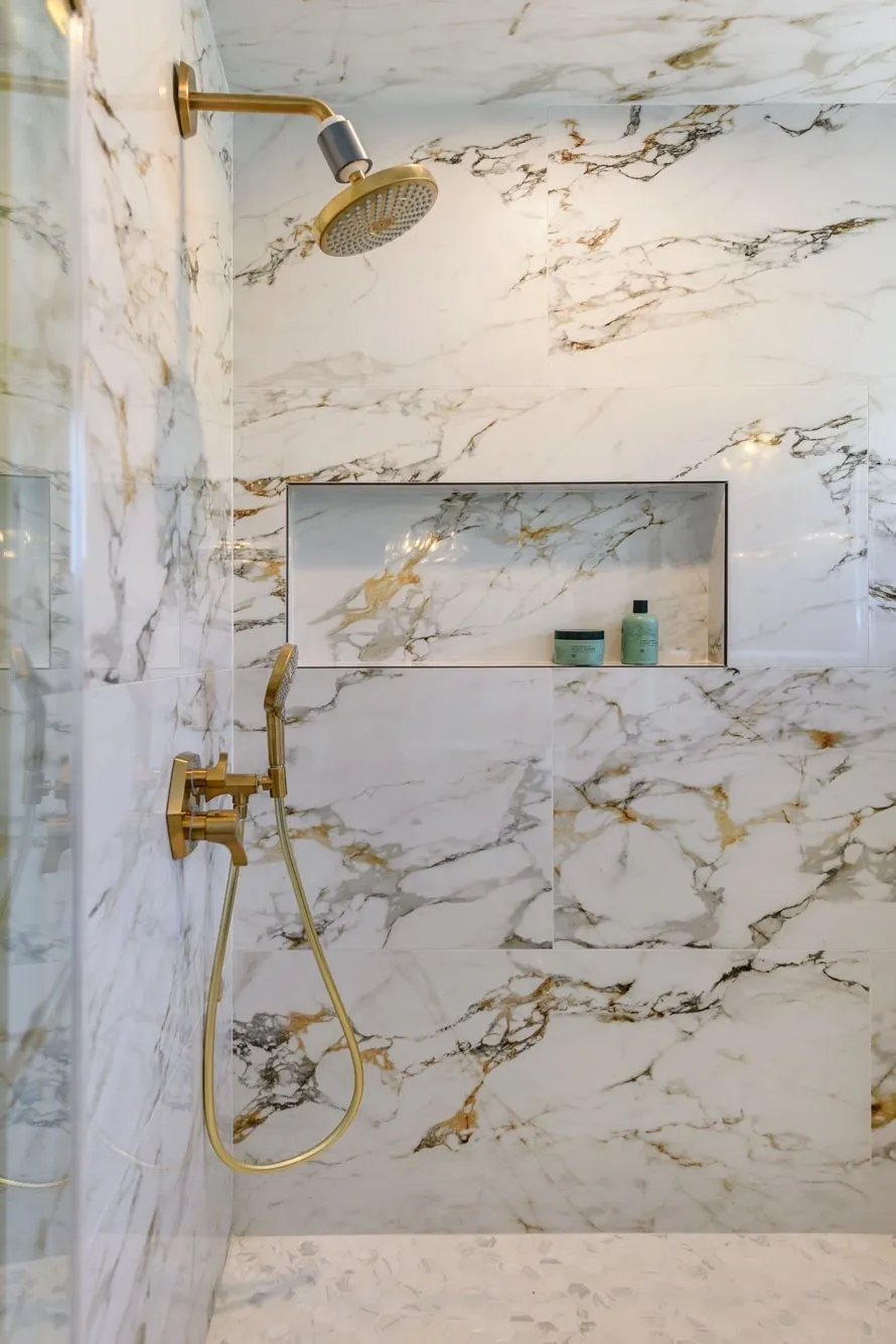 Marble shower with gold fixtures and niche
