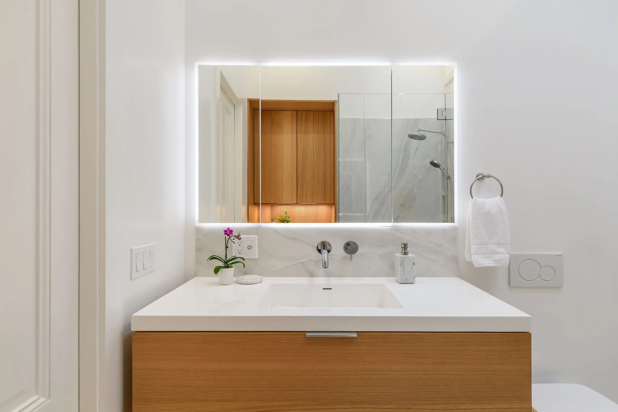 Wooden vanity with backlit mirror and orchid